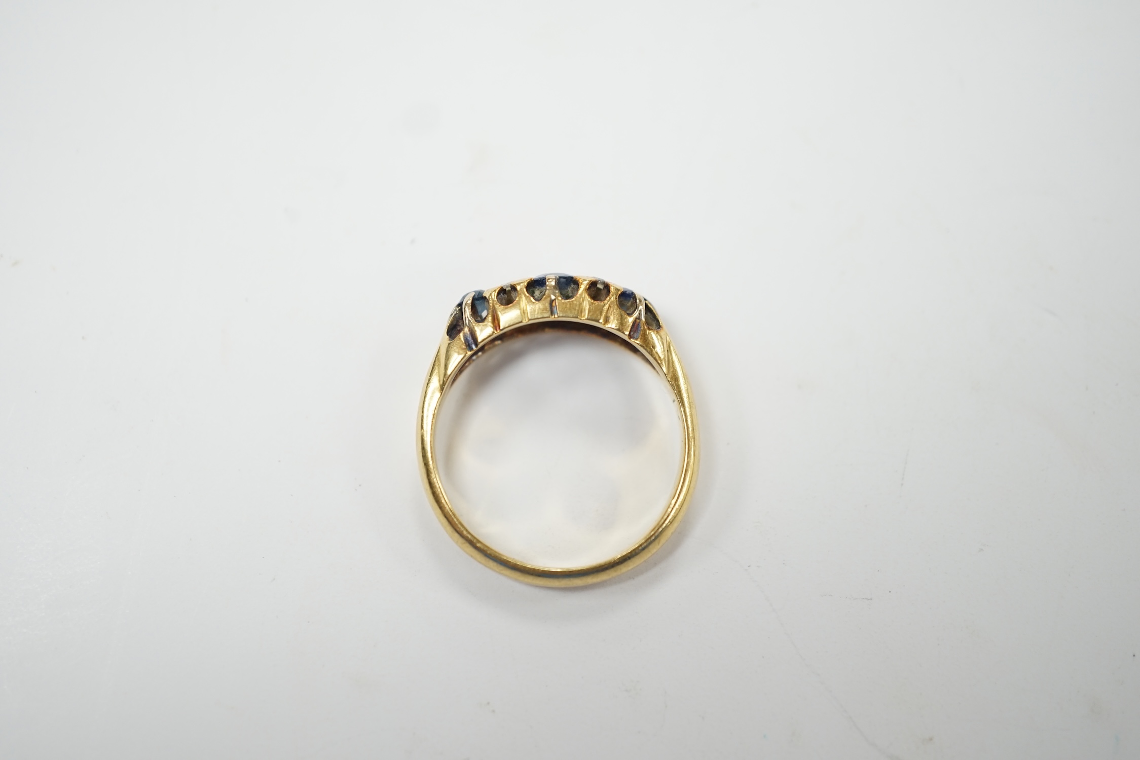 An early 20th century continental yellow metal (stamped 18) and three stone diamond set half hoop ring, with four stone diamond chip spacers, size O, gross weight 4.5 grams. Fair condition.